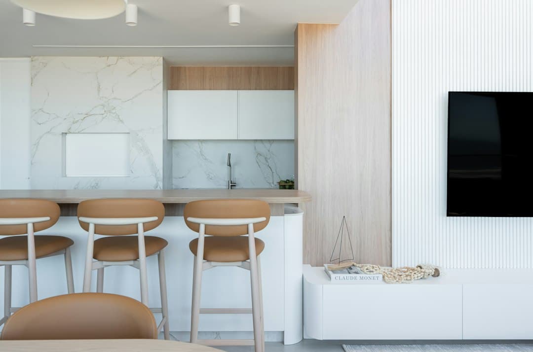 A wall-mounted flat-screen TV in a bright modern living space, the kind of screen used for Digitaline IPTV in 4K
