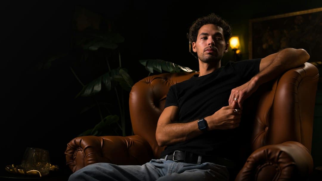 A man relaxing in a leather armchair in a dim room, ready to watch Digitaline IPTV in IPTV Smarters Pro