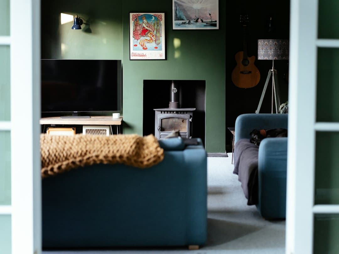 A living room with green walls, a television on a low cabinet and a blue sofa, ready to stream Digitaline IPTV